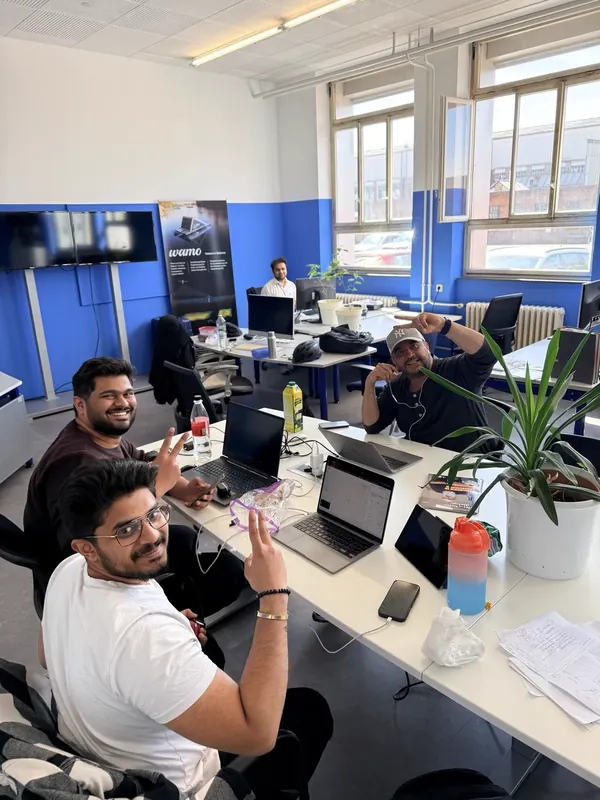 Zwei Kollegen am Schreibtisch im Büro in Darmstadt grüßen in die Kamera