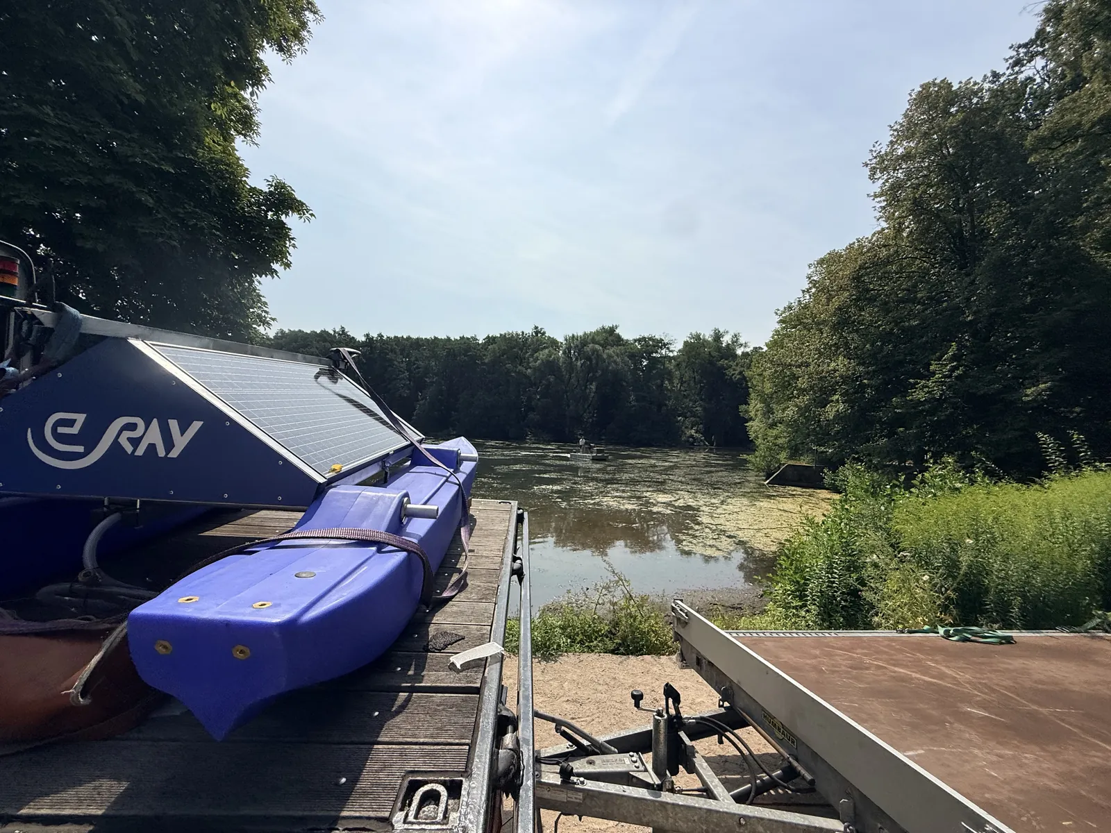 WAMO station on the trailer at the shore of the Backhausteich, with the water surface and its algal mat in the background
